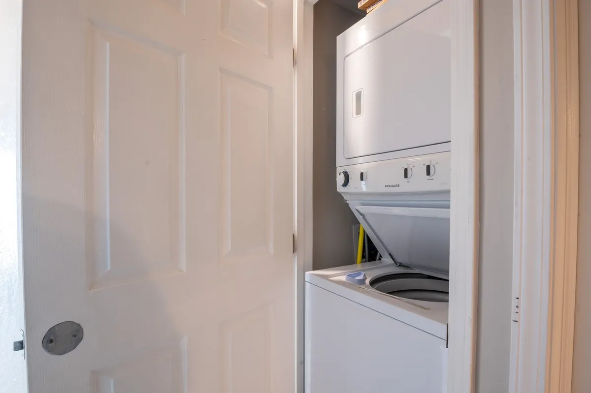 A practical stacked washer and dryer setup is neatly tucked into a closet, with nearby laundry supplies visible, emphasizing the convenience and functionality of in-home laundry options.
