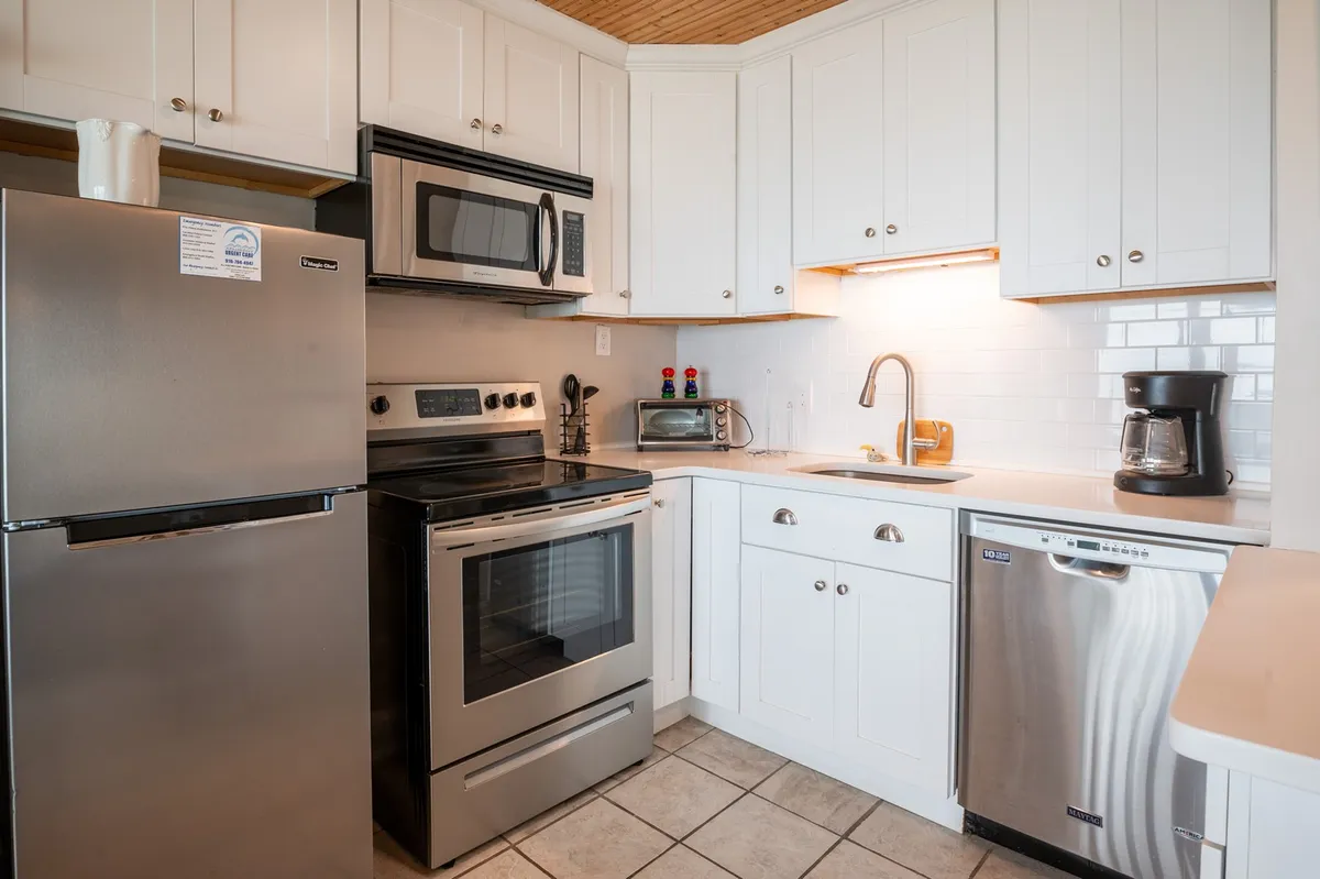 This image highlights a modern kitchen with stainless steel appliances, a spacious countertop, and a clean kitchen sink. The design is open and inviting, emphasizing a functional workspace ideal for preparing meals or gathering for casual conversation.