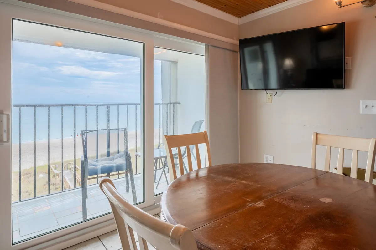 A dining area with a table set for four, placed beside a large window offering unobstructed ocean vistas. The mood is relaxed and inviting, ideal for shared meals or sunrise coffees while overlooking the water.